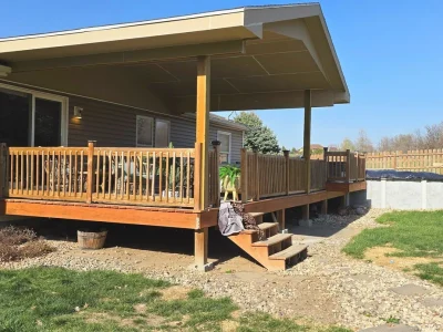 Backyard deck with metal roof covering, wood railings, and built-in support posts